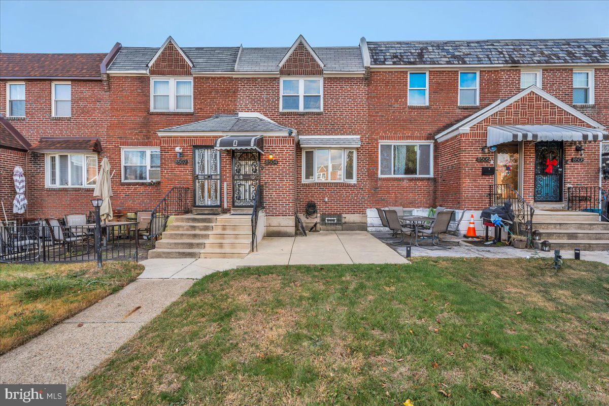 8504 Forrest Avenue Philadelphia, PA 19150 - Photo 1 of 23 a front view of a residential apartment building with a yard table and chairs