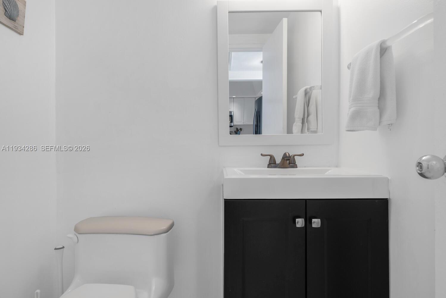 5601 Collins Avenue, Unit 1019 Miami Beach, FL 33140 - Photo 24 of 29 a bathroom with a sink a toilet and a mirror