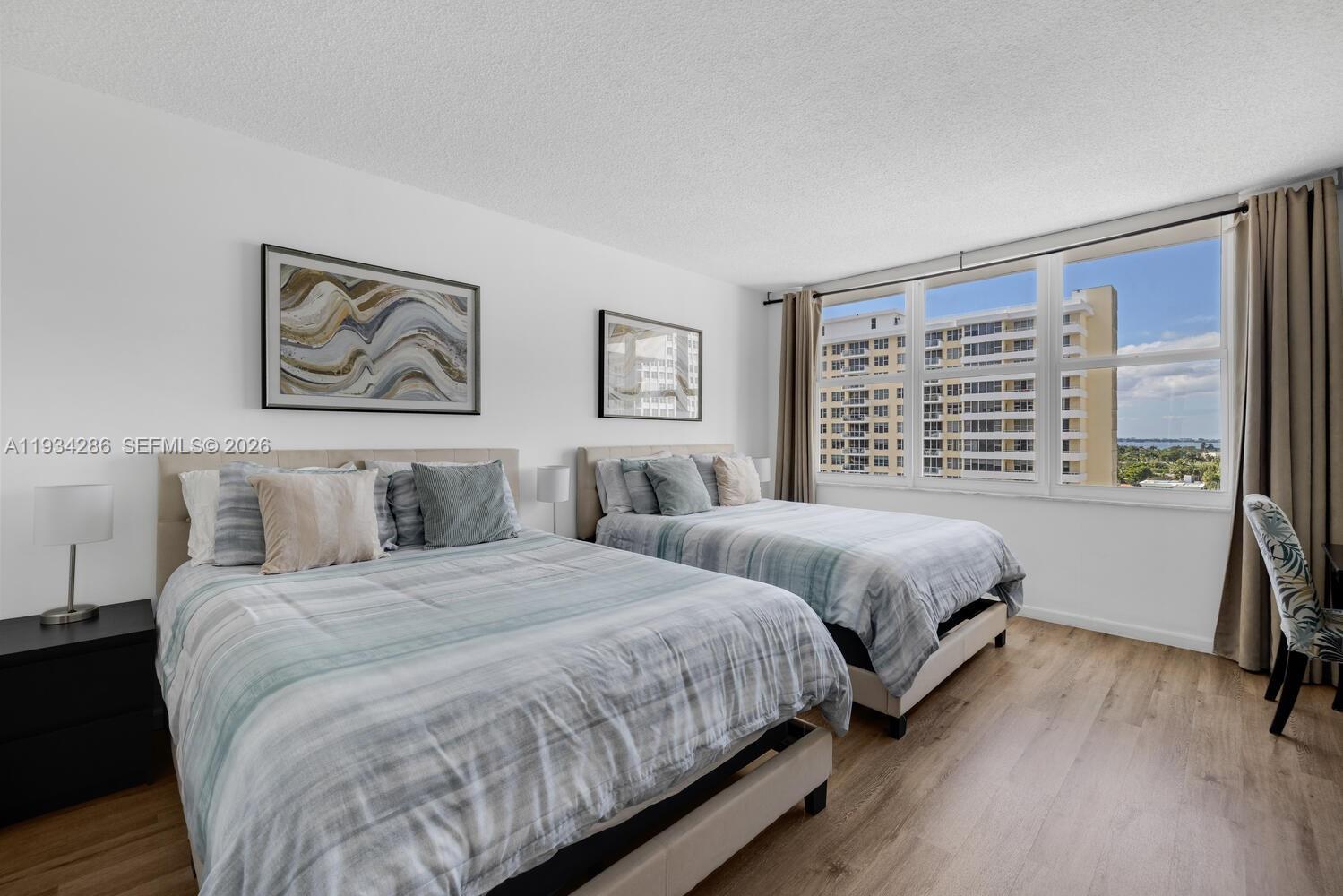 5601 Collins Avenue, Unit 1019 Miami Beach, FL 33140 - Photo 26 of 29 a bedroom with two beds and a large mirror next to a window