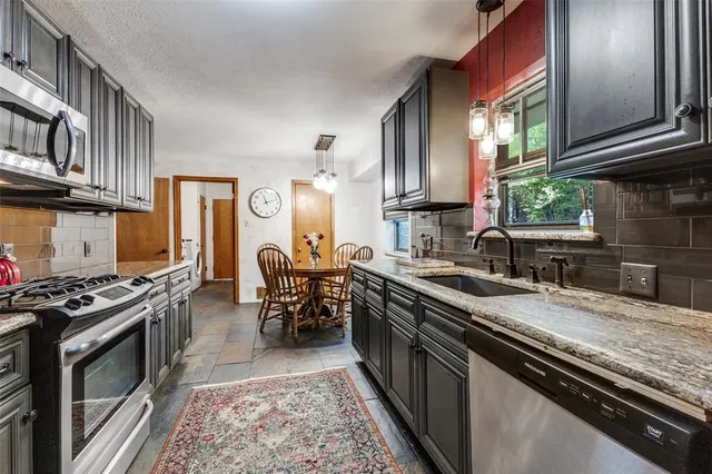 a kitchen with stainless steel appliances granite countertop a stove a sink and a microwave