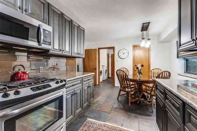 a kitchen with stainless steel appliances granite countertop a stove a sink dishwasher and cabinets with wooden floor