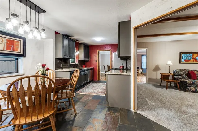 a kitchen with stainless steel appliances kitchen island granite countertop a refrigerator a stove a sink a dining table and chairs with wooden floor