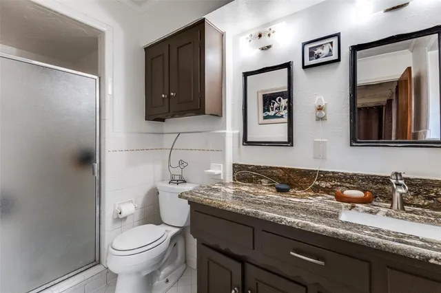 a bathroom with a granite countertop sink toilet and mirror