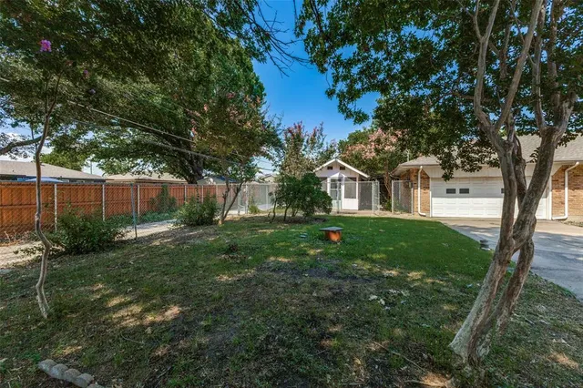 a view of a white house next to a yard with big trees