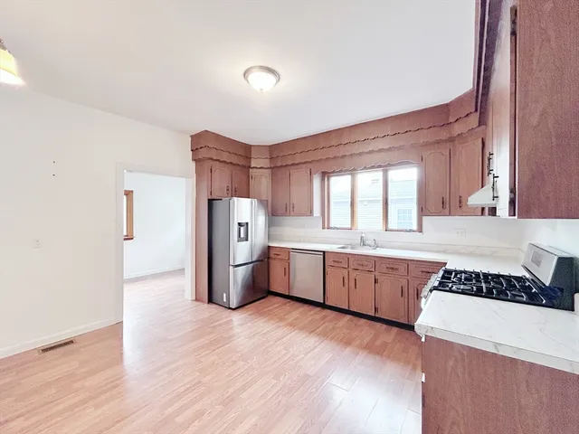 a kitchen with a refrigerator a sink and wooden floor