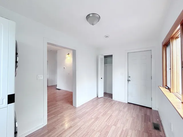 a view of a hallway with wooden floor and cabinet