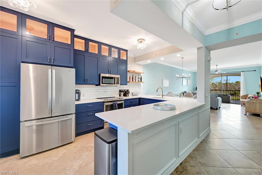 Kitchen with blue cabinets, a chandelier, stainless steel appliances, a peninsula, and pendant lighting