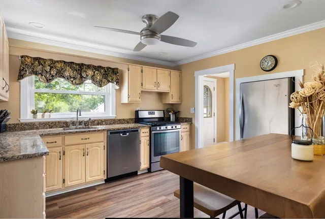 a kitchen with stainless steel appliances granite countertop a stove a refrigerator a sink dishwasher a dining table and chairs with wooden floor