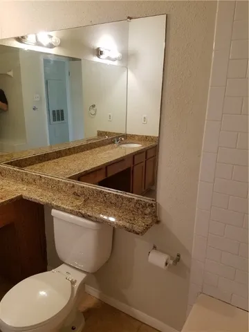 a bathroom with a granite countertop toilet sink and mirror