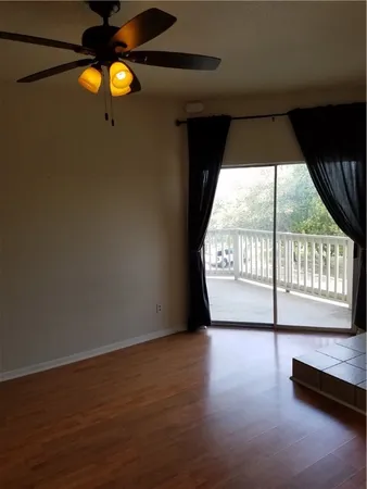 a view of an empty room with wooden floor and windows