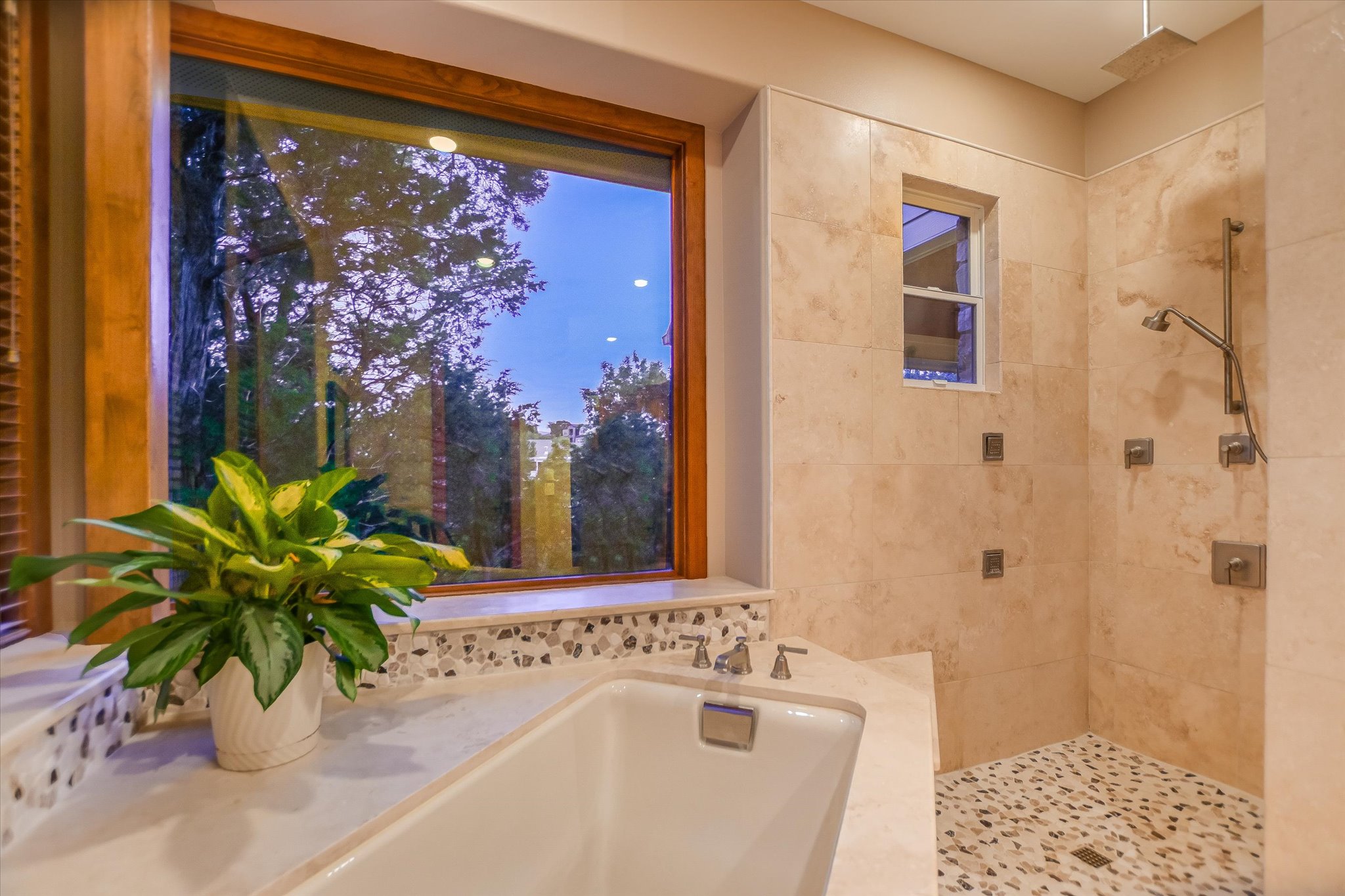 409 Venture Boulevard South Point Venture, TX 78645 - Photo 15 of 37 Soaking tub with mosaic tile surround, large wood-framed window, tiled shower with pebble floor, rain shower head, and multiple body jets