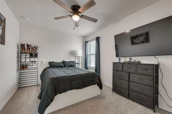 a bedroom with a bed and a flat tv screen on dresser