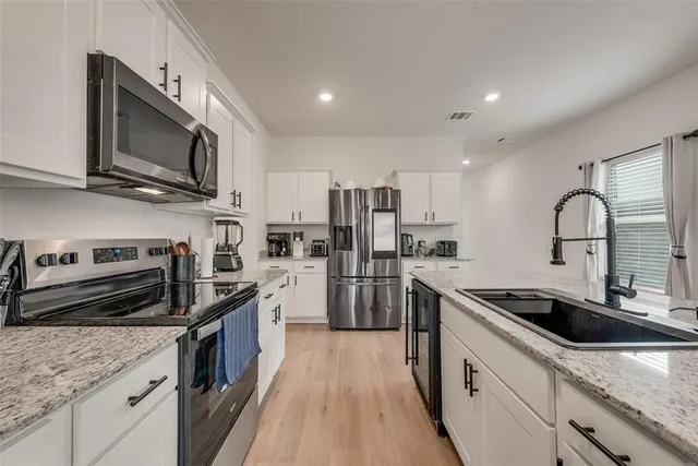 a kitchen with stainless steel appliances granite countertop a sink stove microwave and refrigerator