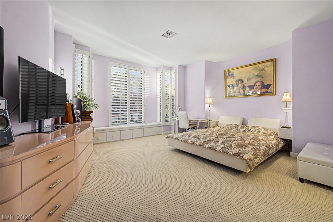46 Gulf Stream Court Las Vegas, NV 89113 - Photo 24 of 62 This spacious bedroom features plantation shutters, soft carpet, and a built-in window seat, creating a serene personal retreat.