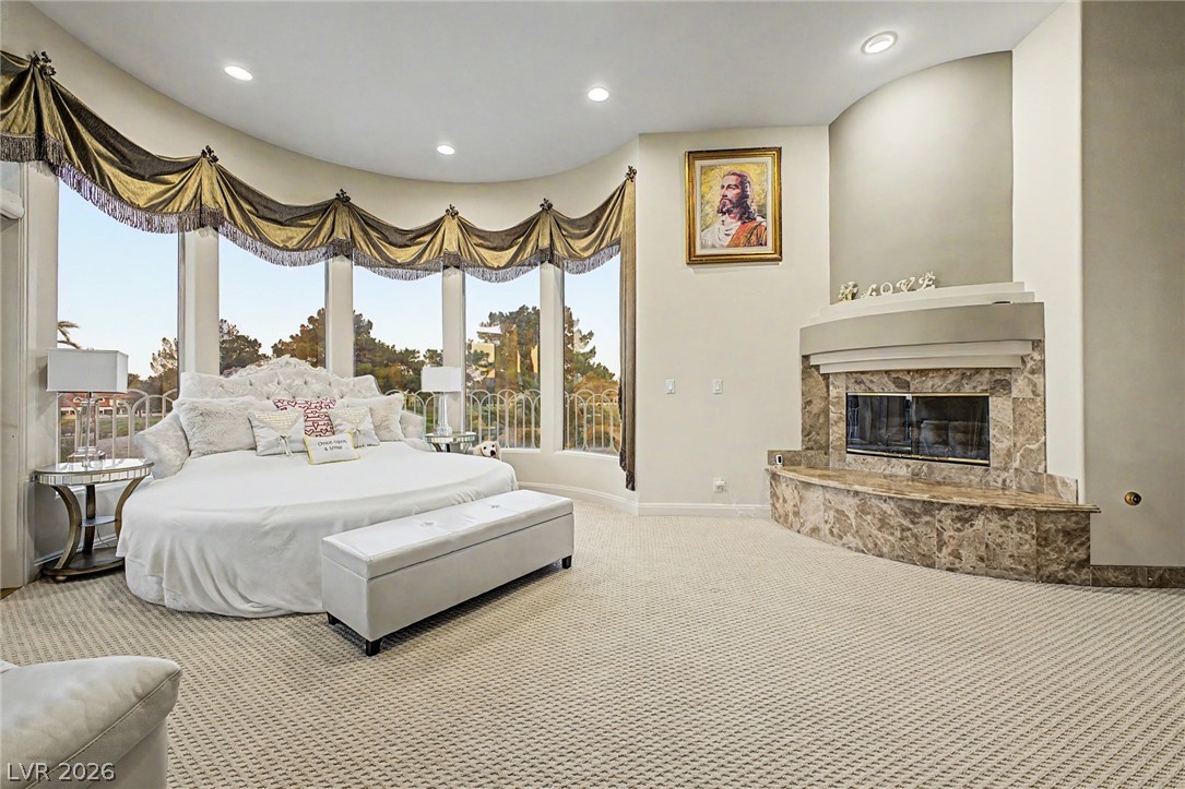 46 Gulf Stream Court Las Vegas, NV 89113 - Photo 34 of 62 This spacious primary bedroom features a curved window wall, carpeted flooring, and a fireplace.