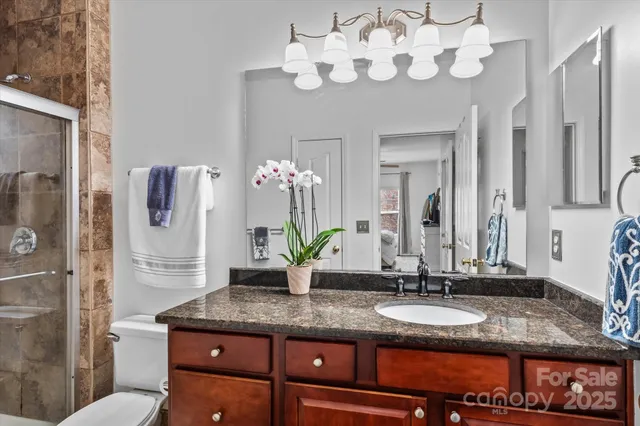 a bathroom with a granite countertop double vanity sink a mirror and shower