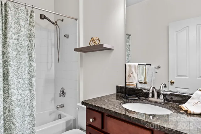 a bathroom with a granite countertop sink a mirror and shower