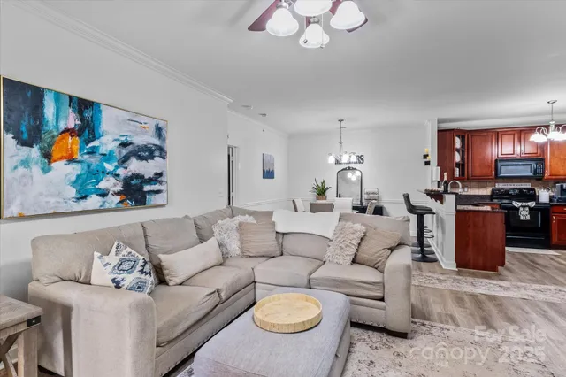 a living room with furniture kitchen view and a chandelier