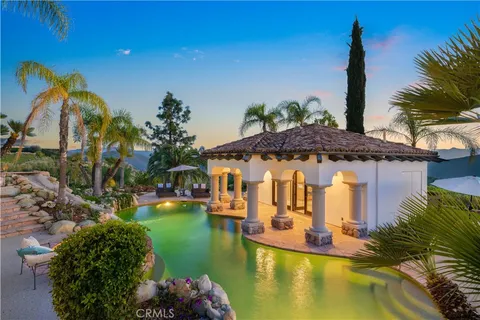 a living room with stainless steel appliances furniture a chandelier and a kitchen view