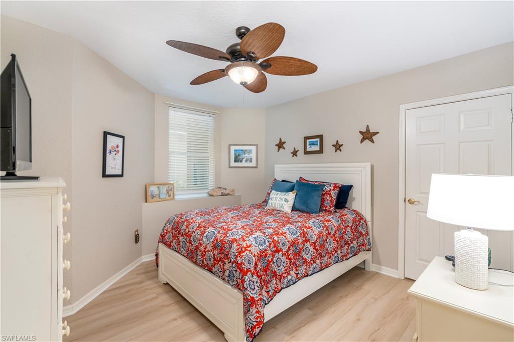 4680 Hawks Nest Way, Unit D103 Naples, FL 34114 - Photo 17 of 41 a bedroom with a bed and a chandelier
