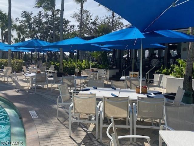 4680 Hawks Nest Way, Unit D103 Naples, FL 34114 - Photo 31 of 41 a view of a patio with a dining table and chairs under an umbrella