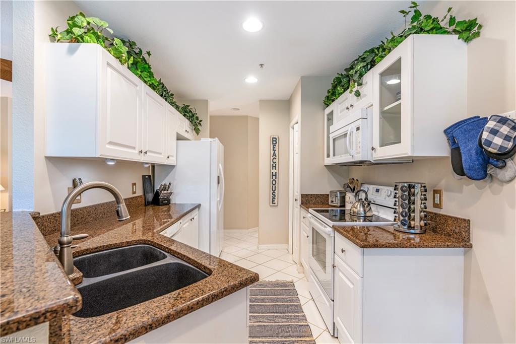 4680 Hawks Nest Way, Unit D103 Naples, FL 34114 - Photo 8 of 41 a kitchen that has a sink and a stove