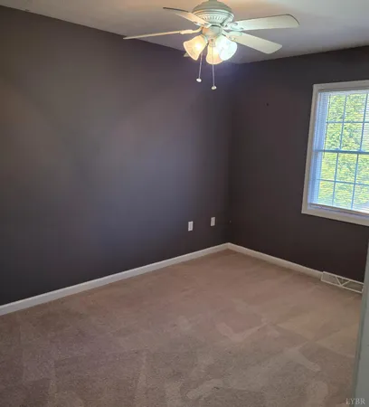 an empty room with a window and a fan