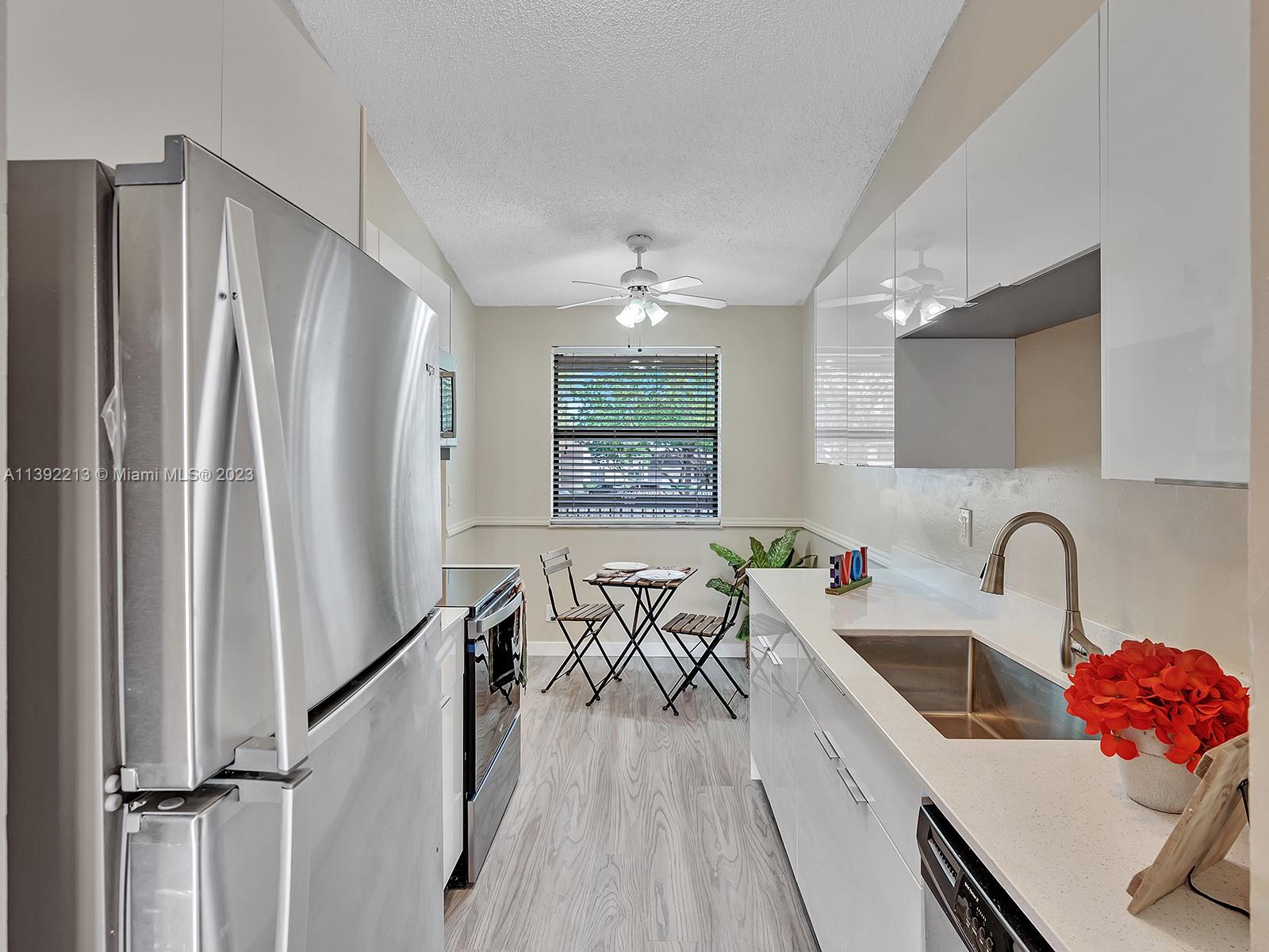 a kitchen with stainless steel appliances a sink a refrigerator and a window