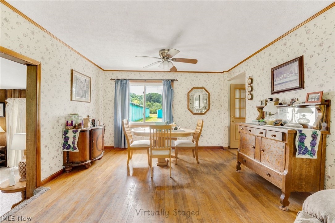 16107 Moseley Road Madison, OH 44057 - Photo 12 of 40 Dining area featuring wood-finish flooring, patterned wallpaper, a ceiling fan, and a window with exterior views