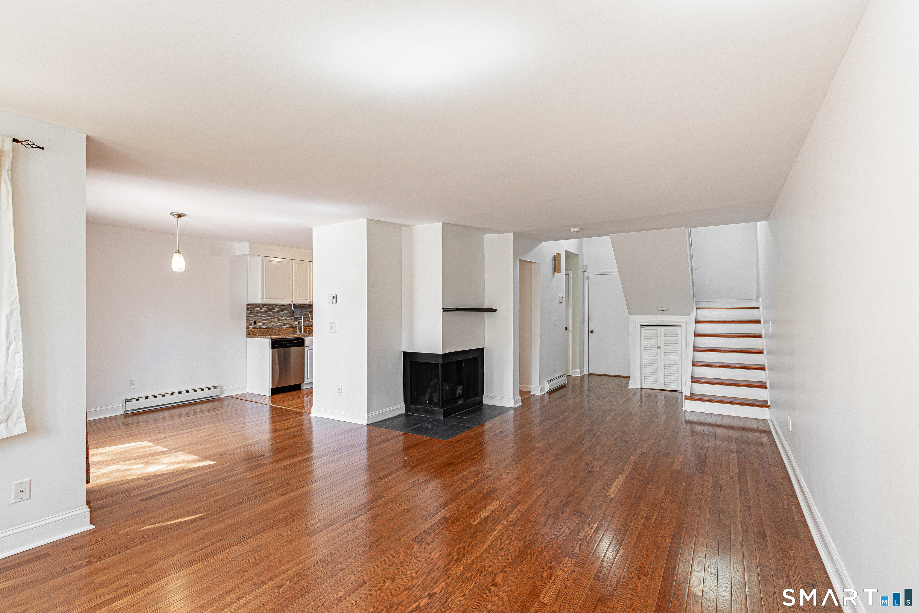 127 Old Farms Road, Unit 127 Torrington, CT 06790 - Photo 13 of 32 an empty room with wooden floor fireplace and windows