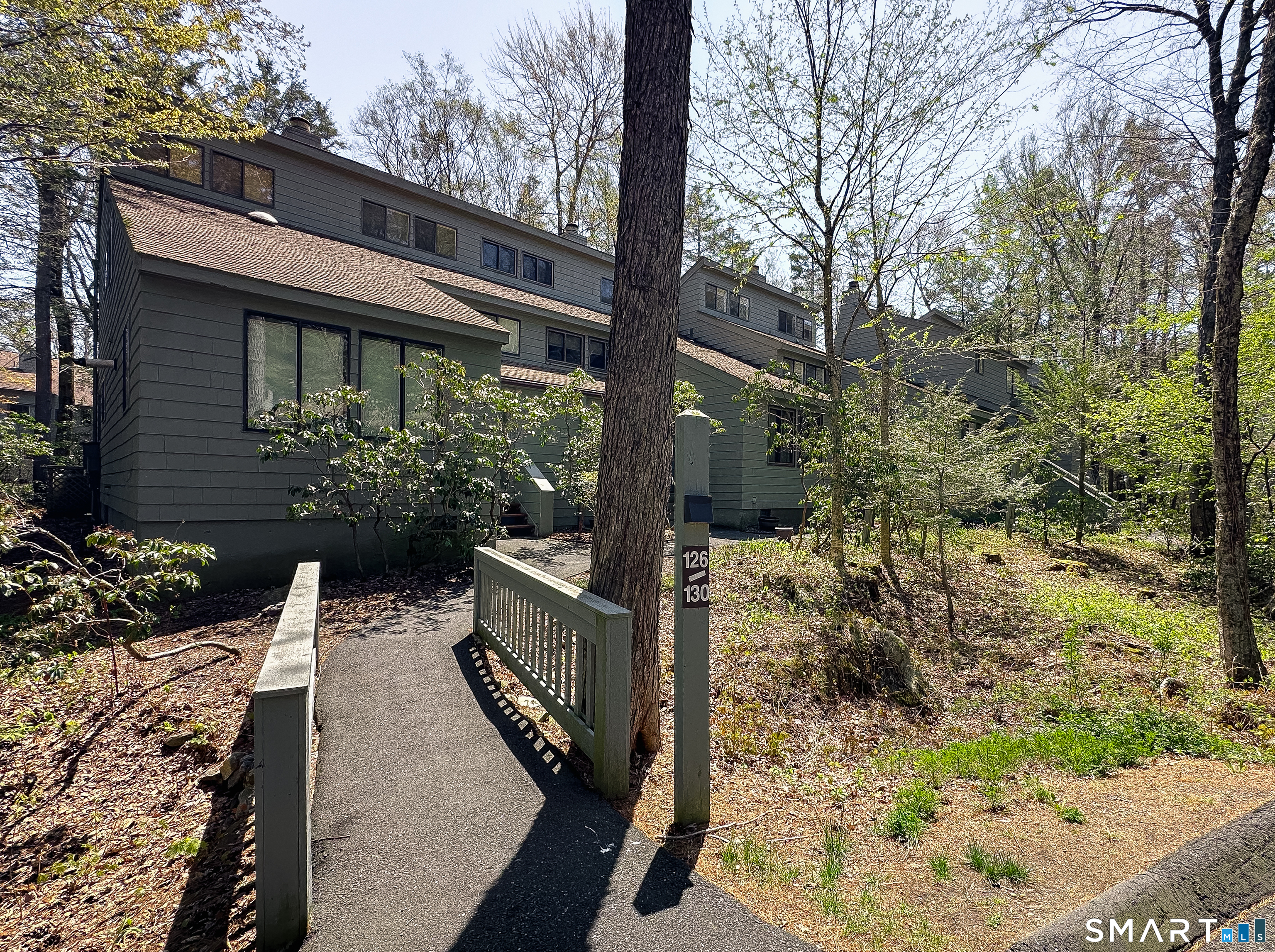 127 Old Farms Road, Unit 127 Torrington, CT 06790 - Photo 2 of 32 a backyard of a house with large trees and plants