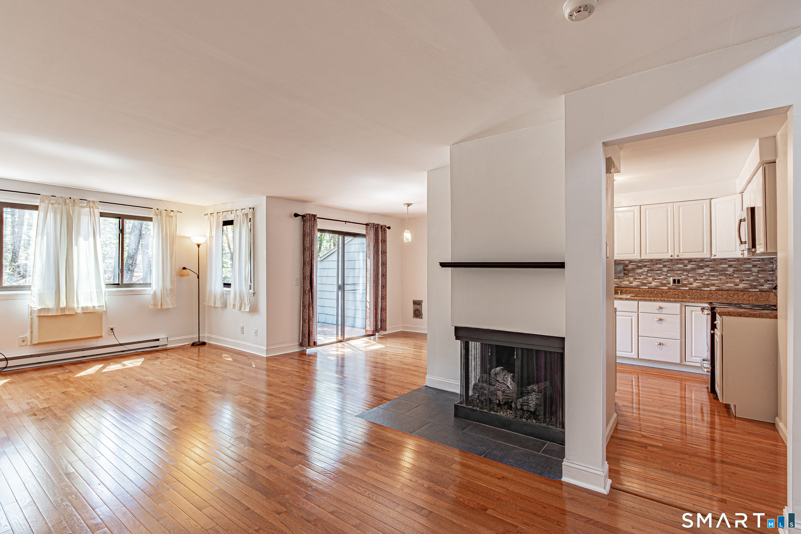 127 Old Farms Road, Unit 127 Torrington, CT 06790 - Photo 9 of 32 a view of a livingroom with wooden floor and a fireplace