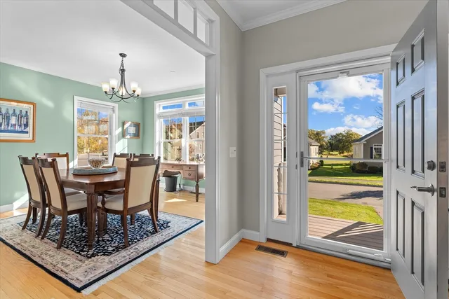 a dining room with wooden floor a chandelier a glass table and chairs