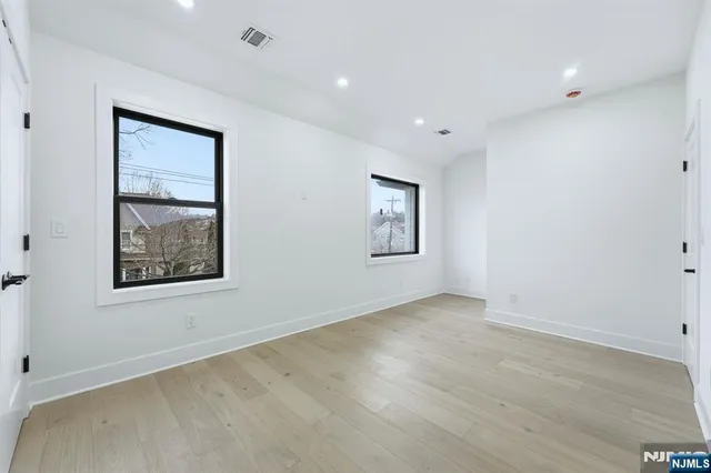 a view of an empty room with window and wooden floor