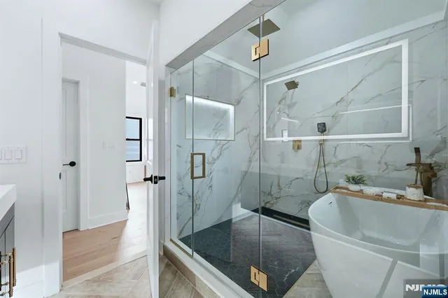 a bathroom with a tub a sink and glass door shower