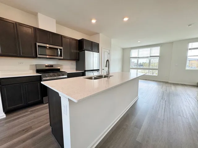 a kitchen with stainless steel appliances a sink a stove a microwave a center island and a window