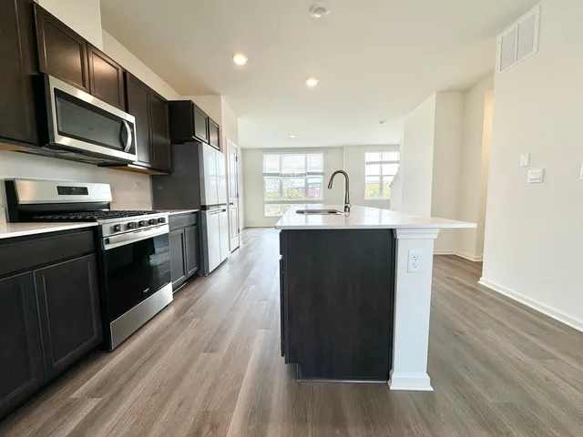 a kitchen with stainless steel appliances granite countertop a sink a stove top oven and wooden floors
