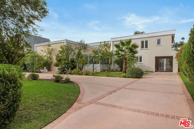 a view of a patio with couches plants and large tree