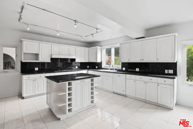 a kitchen with stainless steel appliances granite countertop a stove a sink and white cabinets