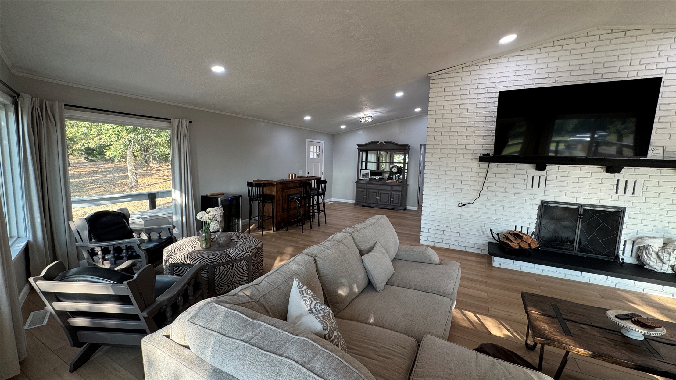 96358 South 4531 Road Vian, OK 74962 - Photo 11 of 58 Wood-finish flooring throughout, white brick fireplace with dark hearth and mantel, recessed lighting, and large windows