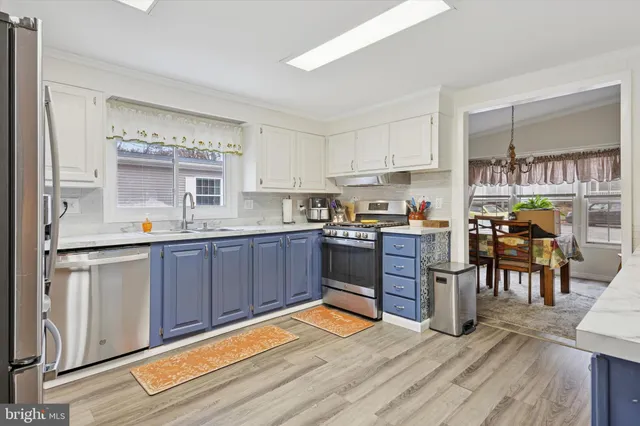 a kitchen with stainless steel appliances granite countertop a stove top oven a sink dishwasher a dining table and chairs with wooden floor