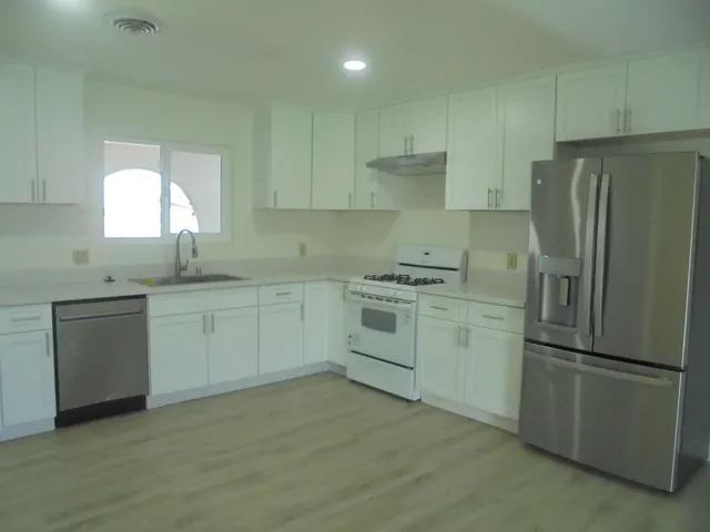 a kitchen with a refrigerator and wooden floor