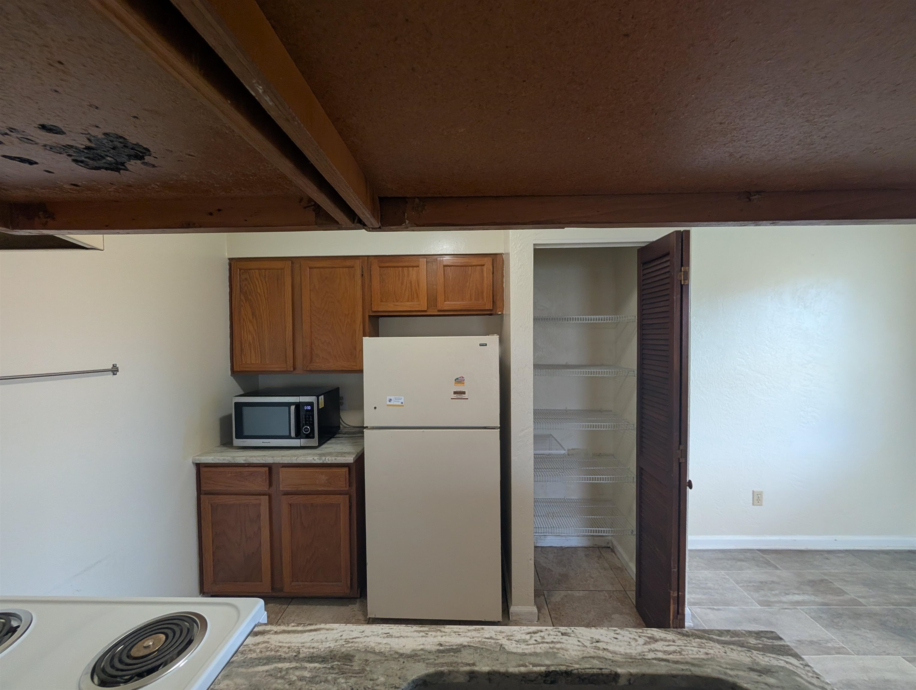 3885 Osprey Circle, Unit D St. Augustine, FL 32086 - Photo 11 of 12 Kitchen with brown cabinets, white appliances, light countertops, beam ceiling, and a textured ceiling