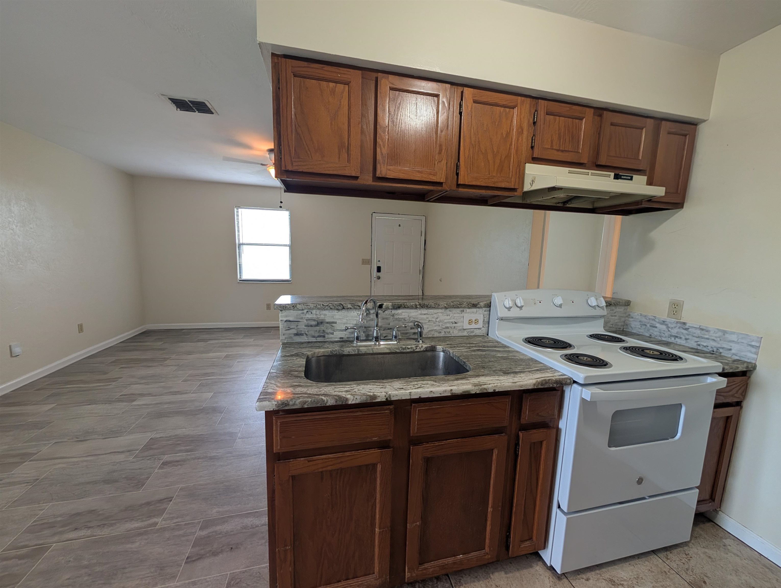 3885 Osprey Circle, Unit D St. Augustine, FL 32086 - Photo 12 of 12 Kitchen featuring electric range, under cabinet range hood, brown cabinets, a peninsula, and open floor plan