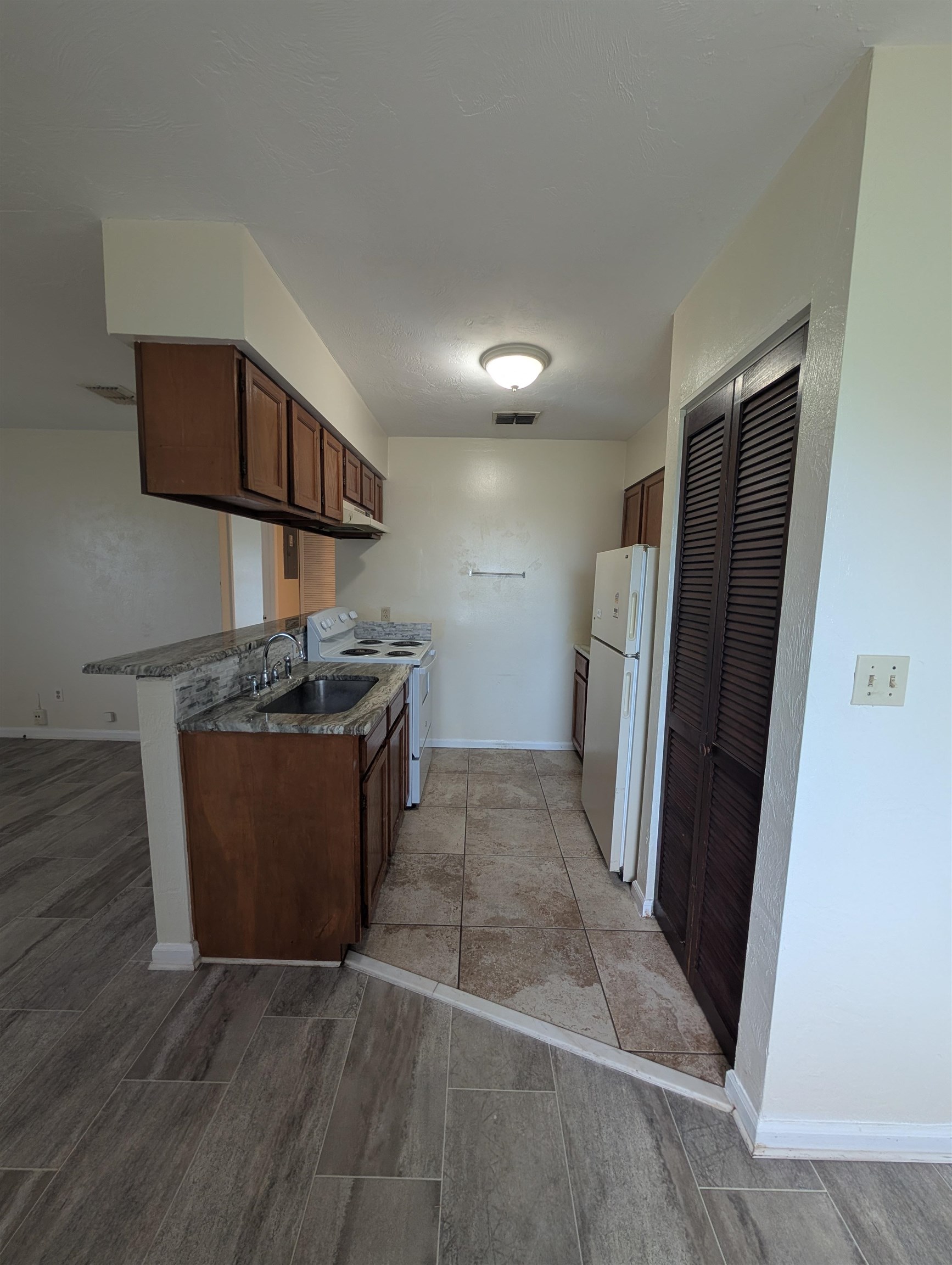3885 Osprey Circle, Unit D St. Augustine, FL 32086 - Photo 10 of 12 Kitchen featuring white appliances, brown cabinetry, and light wood-style flooring
