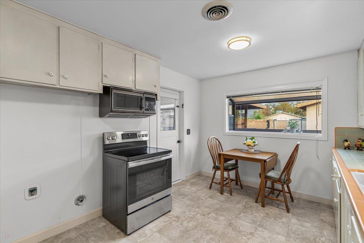 232 Fusco Avenue Modesto, CA 95354 - Photo 15 of 52 a kitchen with stainless steel appliances kitchen island granite countertop a stove top oven a sink a dining table and chairs with wooden floor