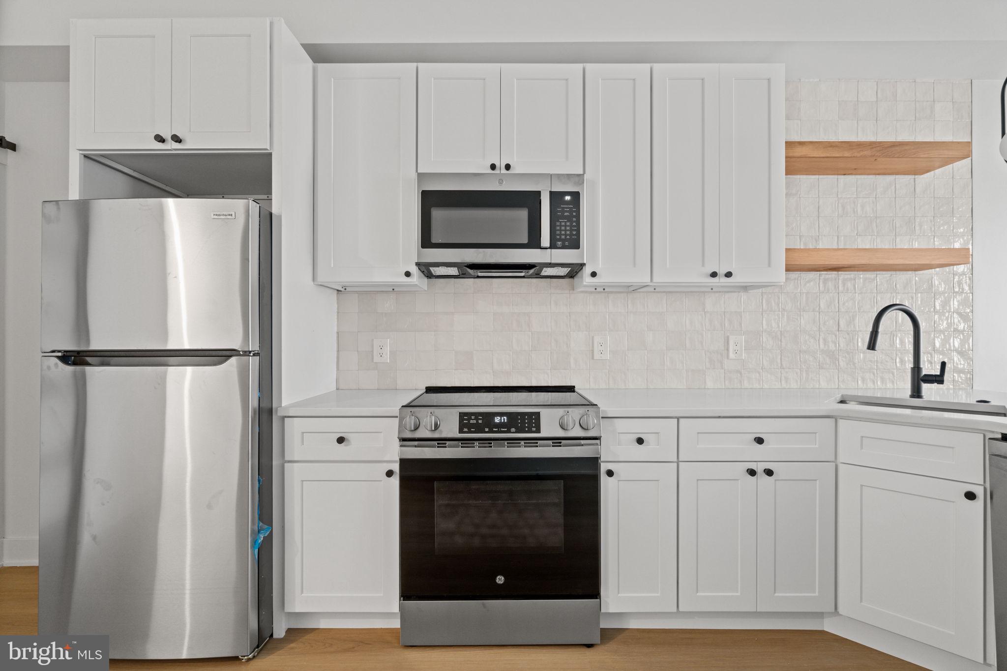 2410 Nicholas Street Philadelphia, PA 19121 - Photo 3 of 55 a kitchen with white cabinets and stainless steel appliances