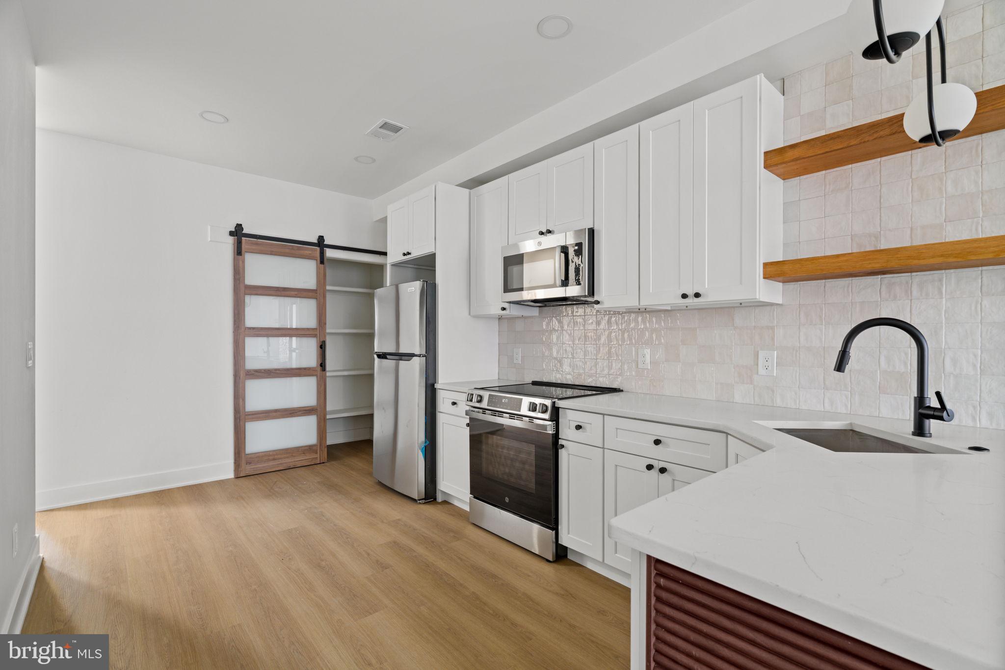 2410 Nicholas Street Philadelphia, PA 19121 - Photo 4 of 55 a kitchen with stainless steel appliances and white cabinets