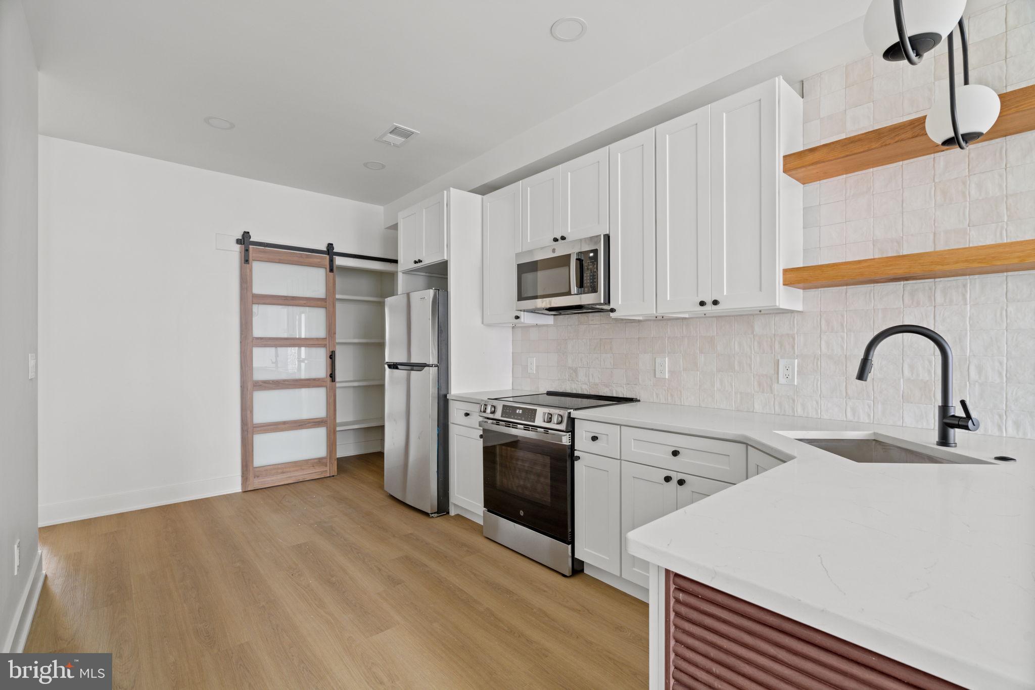 2410 Nicholas Street Philadelphia, PA 19121 - Photo 5 of 55 a kitchen with stainless steel appliances a sink cabinets and a stove top oven