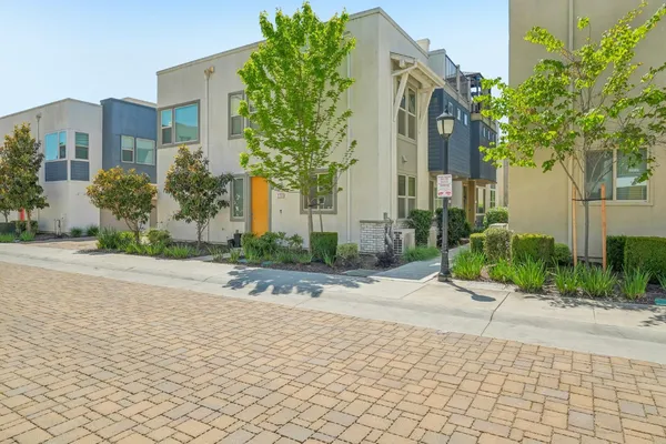 a sidewalk with a building and trees in the background